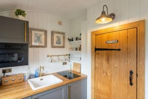 a kitchen with a sink and a wooden door at Secluded Countryside Shepherd's Hut on Working Farm near Audley in Audley