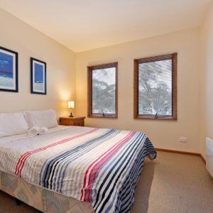 a bedroom with a large bed and two windows at Square Bear in Dinner Plain
