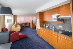 a kitchen with wooden cabinets and a living room at Hotel Höri Inn in Höri +22 photos