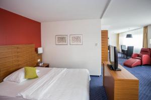 a hotel room with a bed and a flat screen tv at Hotel Höri Inn in Höri