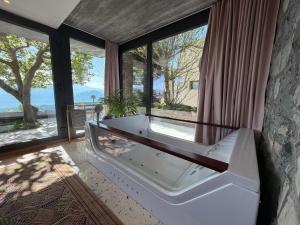a bath tub in a room with large windows at ROMANTIC SUlTE WITH ITS OWN SPA AND OPEN VIEW TO LUGANO in Cademario