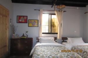 a bedroom with two beds and a window at BIG J'S Farm House in Dhulikhel
