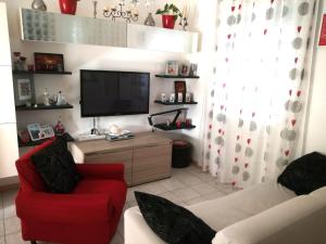 a living room with a red chair and a flat screen tv at Casa Cesano mare in Senigallia