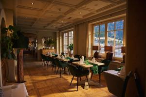 ein Esszimmer mit Tischen, Stühlen und Fenstern in der Unterkunft Hotel Hohenfels in Tannheim