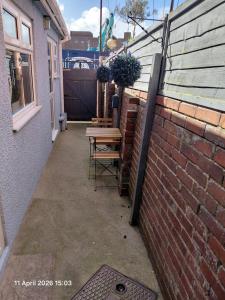 a patio with a table and chairs next to a brick wall at Flat by the sea in Paignton