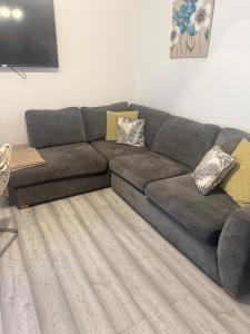 a gray couch in a living room with a wooden floor at HLA Holytown in Mossend