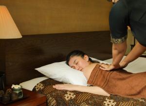 a woman laying on a bed getting a massage at Nawana Sentul City by Alana in Bogor