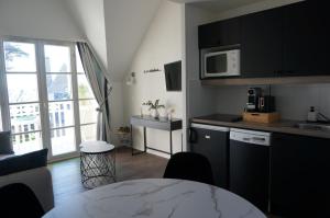 a kitchen with black cabinets and a table in a room at La plage du Trez - Charmant duplex avec vue mer in Bénodet