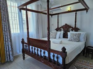 a bedroom with a canopy bed with white sheets and pillows at Greenwood Apartments in Mtwapa