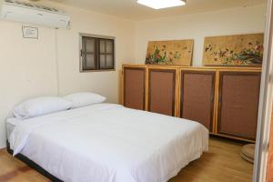 a bedroom with a white bed and wooden cabinets at 청송 한옥호텔 안 in Imjŏn-dong
