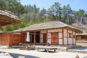 a small hut with a table and a umbrella at 청송 한옥호텔 안 in Imjŏn-dong