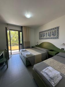 a hotel room with two beds and a window at Hotel Cala Dei Pini in Porto Pino