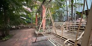 a man sitting on a swing in a garden at Villa Guesthouse Bangkok in Bangkok