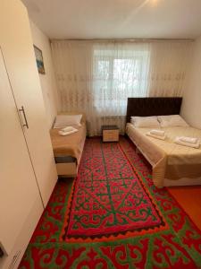 a bedroom with two beds and a red carpet at Kf guest house 2 in Shabdan
