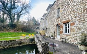 a stone building with a pond in front of it at Le Bief in Pont-et-Massène