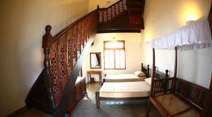 a bedroom with two beds and a stair case at Monsoon Villa in Puttalam