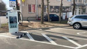 a gas pump in a parking lot with a car at Birch Alley Self Check-In, EV station in Panevėžys