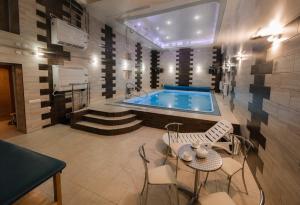 a bathroom with a swimming pool and a table and chairs at SPA Villa Jasmin in Truskavets