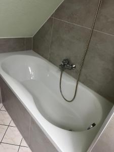a white bath tub with a hose in a bathroom at FeWo im Forsthaus in Marktredwitz +12 photos