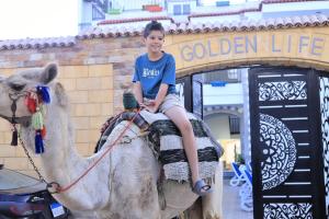 a young boy sitting on a camel in front of a sign at Villa golden life apartments, new property with pool access in Luxor