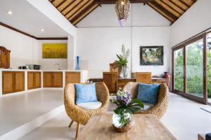 a living room with wicker chairs and a table at Villa Kami Ubud in Ubud