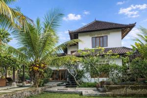 a house with palm trees in front of it at Villa Kami Ubud in Ubud