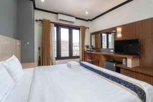 a bedroom with a large white bed and a television at Lucky city hotel in Vientiane