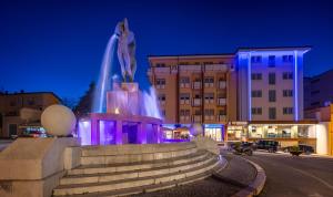 a fountain in the middle of a city at night at Hotel Castello in LʼAquila
