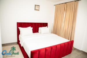 a bed with a red headboard in a room at OASIS PARK RESIDENCE in East Legon