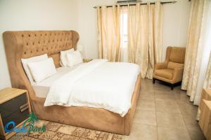 a bedroom with a large bed and a chair at OASIS PARK RESIDENCE in East Legon