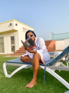 a woman sitting on a chair reading a book at OASIS PARK RESIDENCE in East Legon