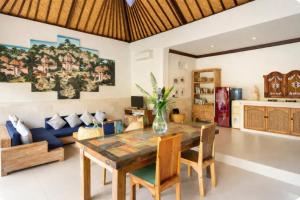 a dining room with a table and a couch at Villa Kami Ubud in Ubud