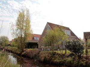 a large house next to a river with trees at Appealing bungalow with garden in Breskens