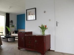 a living room with a vase of flowers on a dresser at Appealing bungalow with garden in Breskens