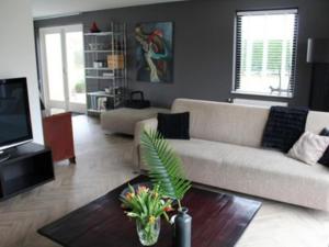 a living room with a couch and a table at Appealing bungalow with garden in Breskens +85 photos