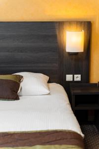 a bedroom with a bed and a lamp and a table at Logis Hôtel Restaurant des Châteaux in Azay-le-Rideau