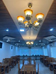 a dining room with tables and chairs and chandeliers at Kuyal Corbett Resort in Rāmnagar