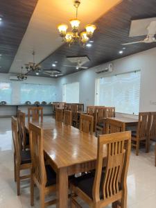 a dining room with a large wooden table and chairs at Kuyal Corbett Resort in Rāmnagar +26 photos