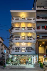 a tall white building with tables in front of it at Lucky city hotel in Vientiane