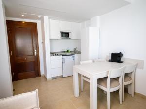 a white kitchen with a white table and chairs at Prope Mare Apartamentos in Cala Millor