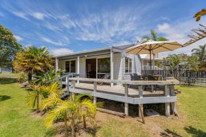 a tiny house with a deck and an umbrella at Sea Breezes in Matarangi