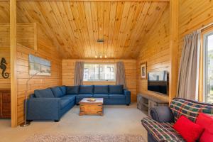 a living room with a blue couch and a tv at Sea Breezes in Matarangi