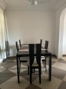 a black dining room table with chairs and a ceiling fan at Hallmark Apartments -1 in Accra +6 photos