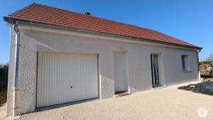 a garage with a large white garage door at Le Refuge de Coccinette in Essey