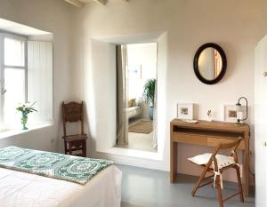 a bedroom with a bed and a desk and a mirror at Villa Halara in Ano Mera