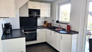 a kitchen with white cabinets and black counter tops at PONTUS Ferienwohnung FeWo 1 in Zislow