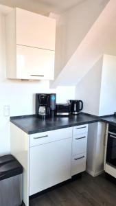 a kitchen with white cabinets and a black counter top at PONTUS Ferienwohnung FeWo 1 in Zislow +11 photos