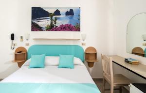 a bedroom with a blue bed and a desk at Hotel Carmencita in Anacapri