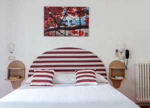 a bedroom with a white bed with red and white pillows at Hotel Carmencita in Anacapri