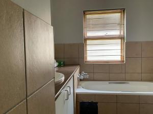 a bathroom with a tub and a sink and a window at Lekoa Lifestyle Apartment in Vanderbijlpark +12 photos